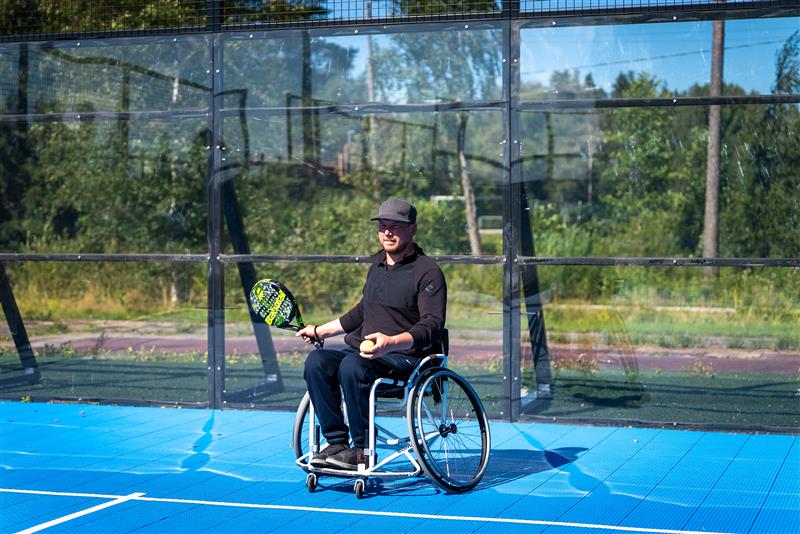 Pyörätuolia käyttävä pelaaja padelkentällä.
